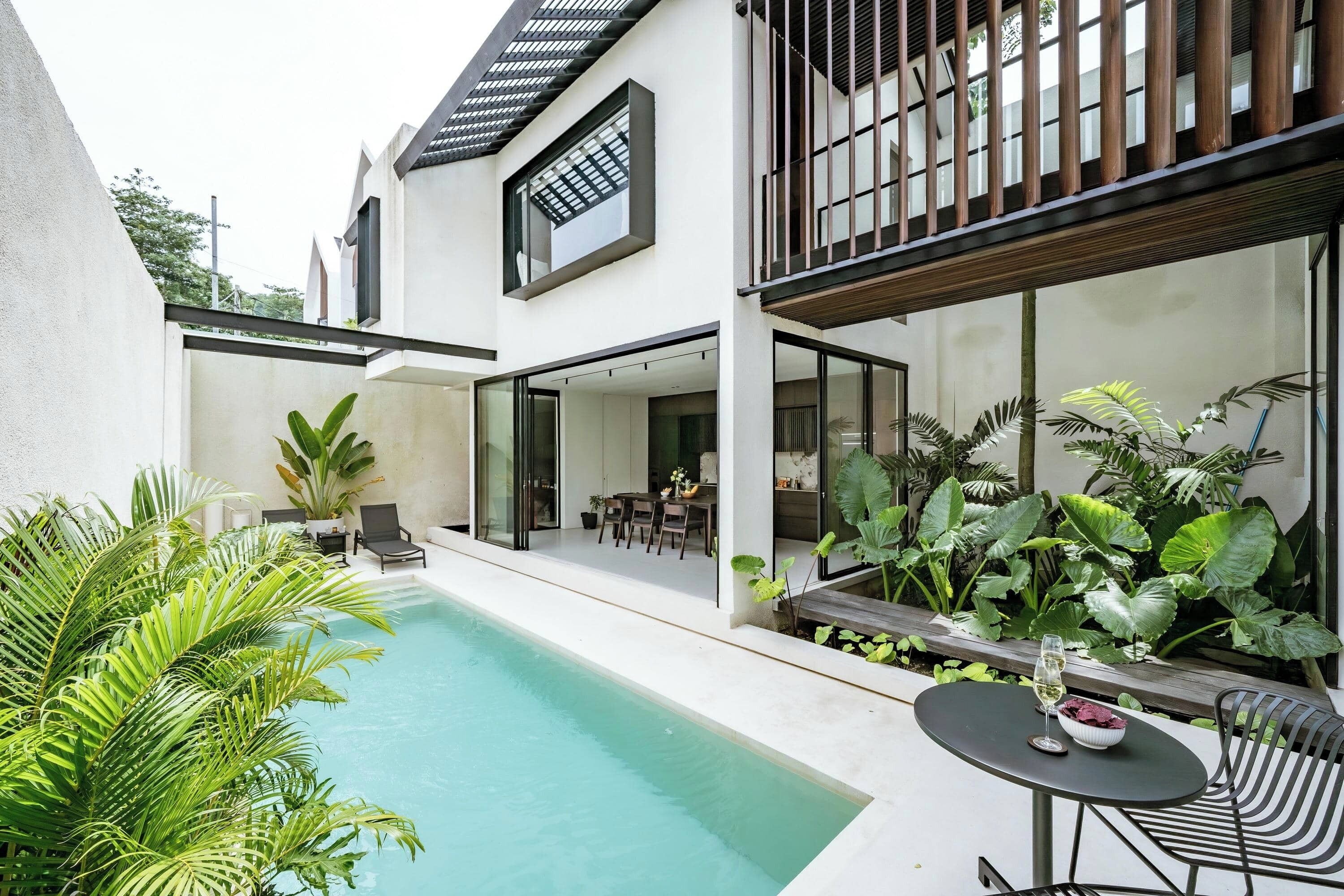 Ein modernes Haus mit Swimmingpool, Sitzgelegenheiten im Freien und üppiger Bepflanzung.