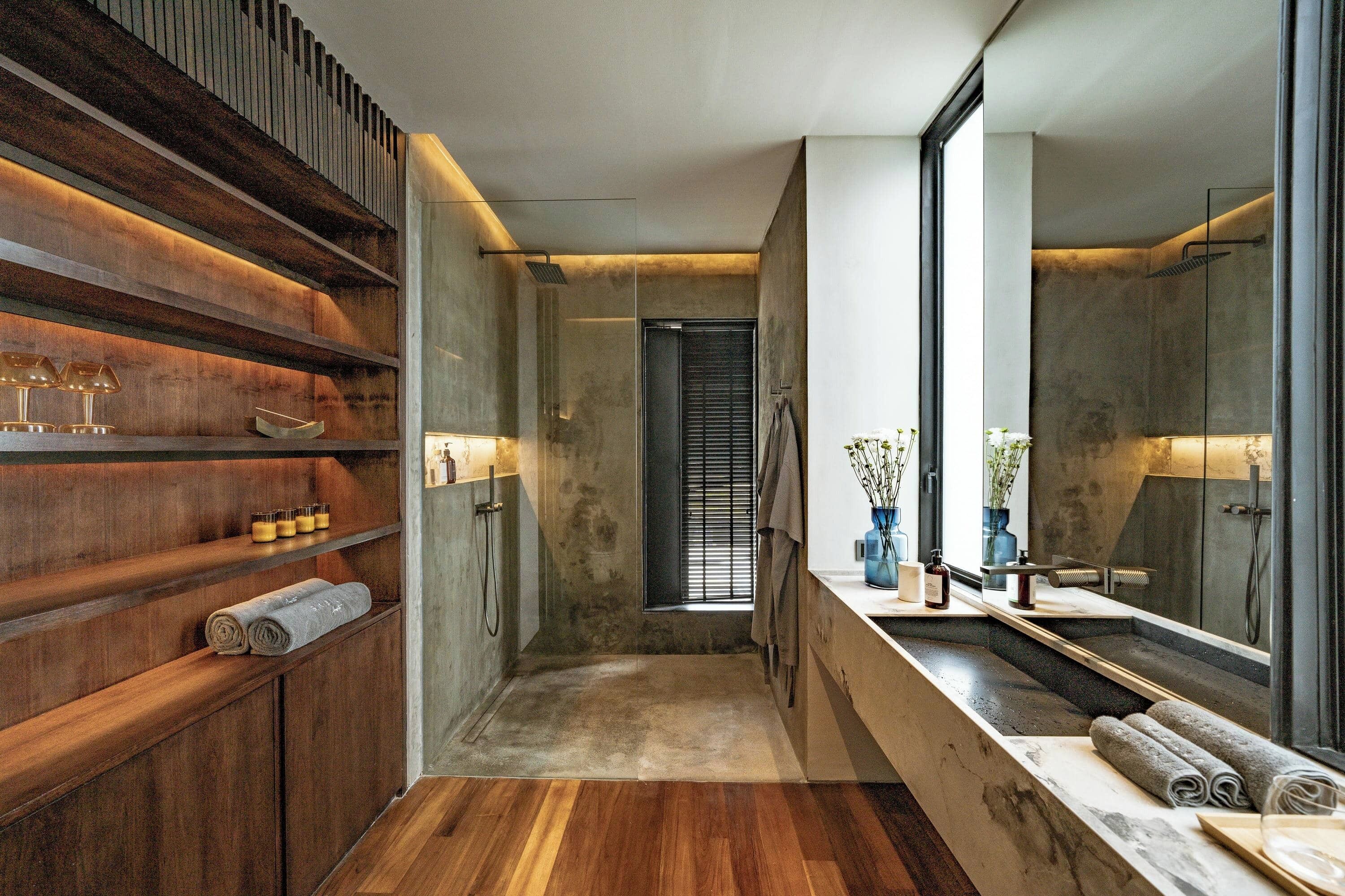 A modern bathroom with wooden shelves, a large mirror, and a shower area.