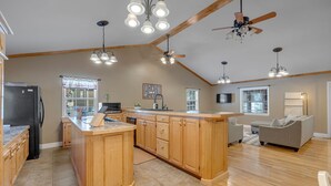 Une cuisine spacieuse avec des meubles en bois, un îlot central et un ventilateur de plafond.