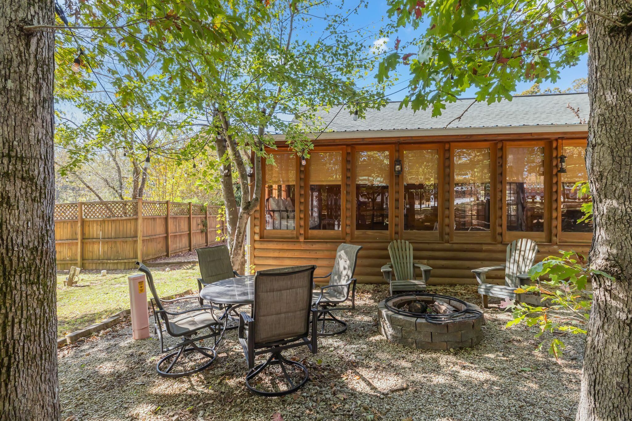 A log cabin with a covered patio, outdoor seating, and a fire pit.