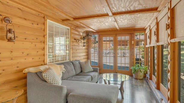 L’intérieur d’un chalet confortable, avec une grande banquette d’angle grise, une petite table en verre et une plante en pot.