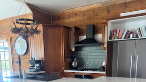 Cucina con rivestimenti in legno, piano di lavoro in marmo, macchina del caffè, fornello a gas e libreria.