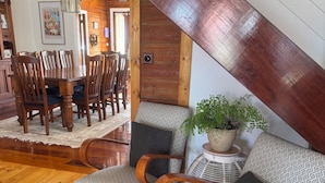 Una scala in legno con finitura scura, un'area pranzo con sedie e tavolo in legno, e una pianta in vaso su un tavolino.