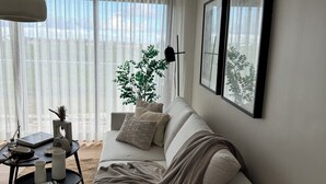 A modern living room with a sofa, a coffee table, and a potted plant. - Xuite Home One Bedroom Suite (Punta Cana)