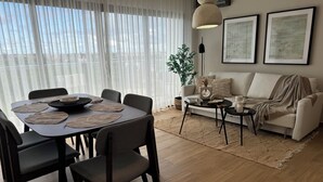 A modern living room with a dining area, featuring a sofa, coffee table, and dining table with chairs. - Xuite Home One Bedroom Suite (Punta Cana)