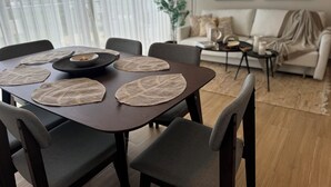 A dining area with a table set for four, surrounded by chairs. A sofa and a small side table with a lamp are visible in the background. - Xuite Home One Bedroom Suite (Punta Cana)