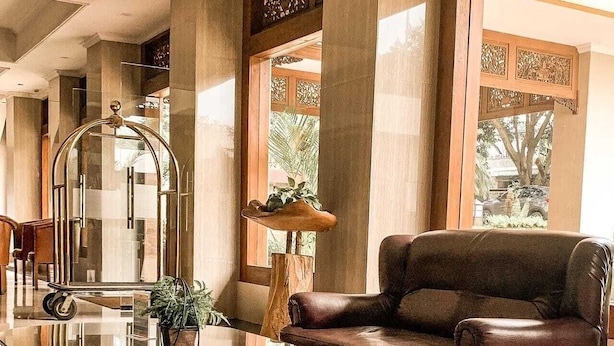 A lobby with a leather sofa, a glass coffee table, and a wooden side table. - Rizen Padjadjaran Hotel (Bogor)