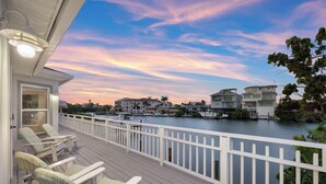 A waterfront property with a deck, lounge chairs, and a view of the water and neighboring houses. - Beach Dayz | Walk to Beach, Restaurants, Boat Dock & More (Bonita Springs)