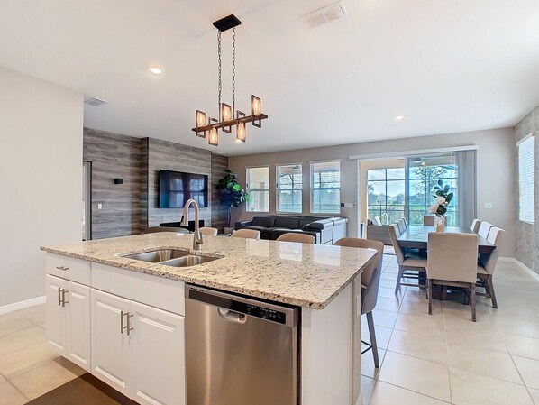 A modern kitchen with a central island, stainless steel appliances, and a dining area with a large table and chairs.
