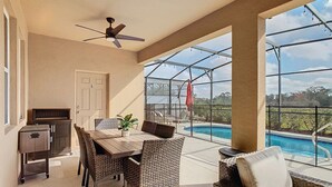 Une terrasse couverte avec une piscine, des meubles en osier et un ventilateur de plafond.