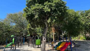 Explore the park-like playground with a slide and climbing frames amidst lush greenery.