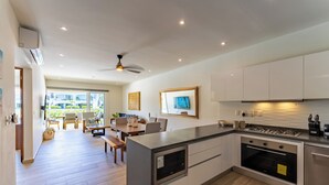 Uma cozinha moderna com uma ilha central, forno embutido e armários brancos.