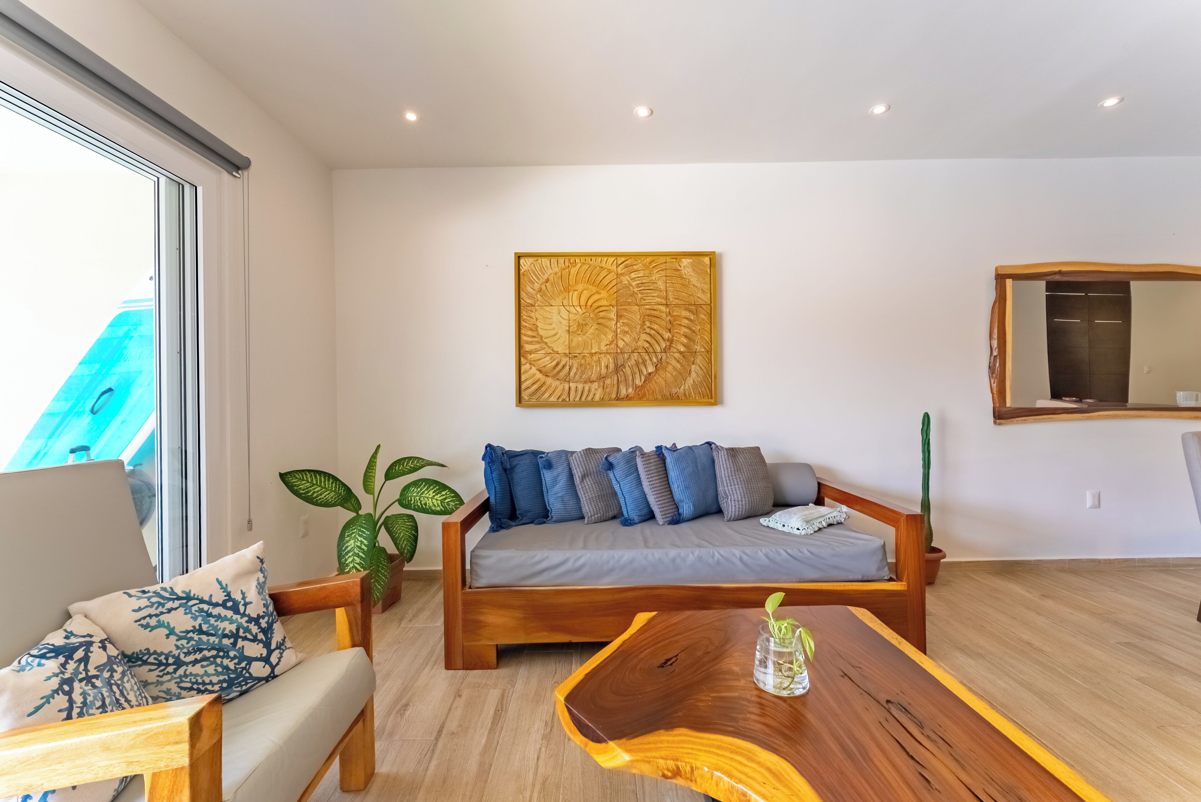 Una sala de estar moderna con un sofá de madera, una mesa de centro y un ventanal grande.