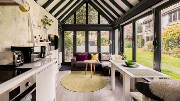 A conservatory with a kitchen, seating area, and large windows. - Robin`s Nest, 1 bedroom near Wimbledon (London)