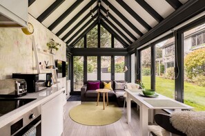 Un invernadero con cocina, zona de estar y ventanas grandes.