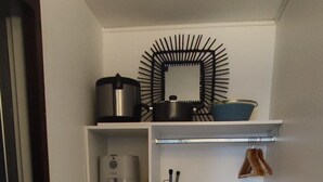 A compact kitchen with a white refrigerator, a microwave, and a coffee maker on a shelf. - Studio Voile au vent (La Trinité)