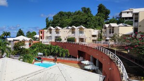 A resort with multiple buildings, a swimming pool, and a curved bridge. - Studio Voile au vent (La Trinité)