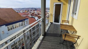 Een balkon met uitzicht op een stadsbeeld, een houten bank en een deur.