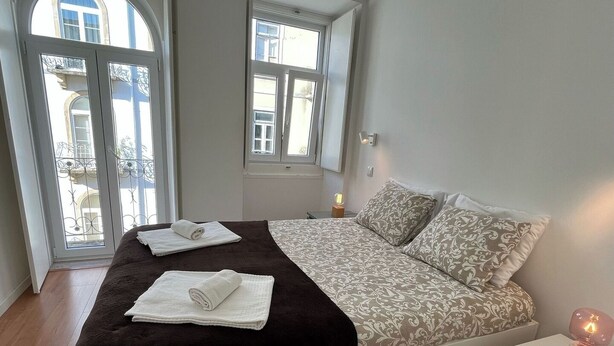 Een slaapkamer met een bed, twee nachtkastjes, een raam en een deur.