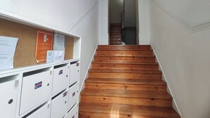 Een wenteltrap met houten treden die uitkomt op een plateau, met witte muren en een prikbord met mededelingen.