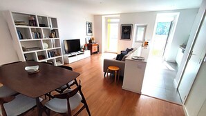 Een moderne woonruimte met een eethoek, een bank, een televisie en een boekenkast.