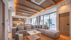Un salon moderne avec un canapé d’angle, une table basse et une cuisine en arrière-plan.