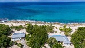 A beachfront property with two houses, a swimming pool, and a view of the ocean.