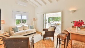 A spacious living area with a sofa, chairs, a dining table, and a view of the outdoors.