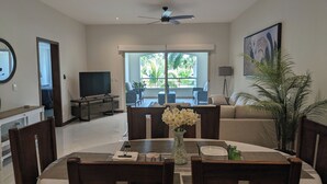 Un comedor con una mesa dispuesta para cuatro, un televisor al fondo y vistas del patio exterior.
