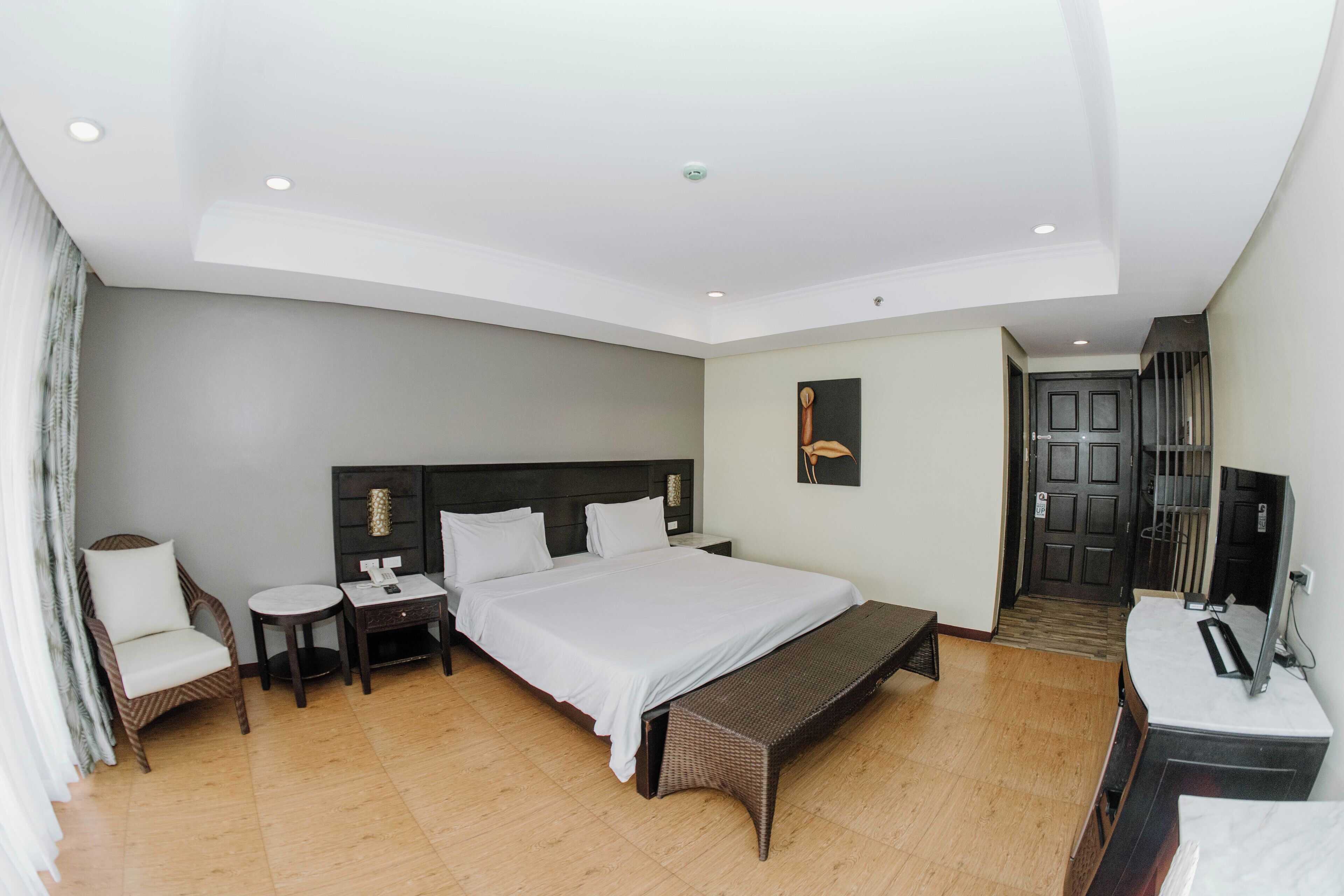 A modern hotel room with a large bed, a desk, a chair, and a television.