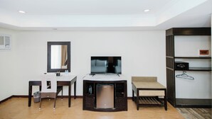 A compact hotel room with a desk, a small refrigerator, a TV, a chair, and a wardrobe. - Cebu Westown Lagoon-Partywing (Mandaue)