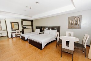 Une chambre d’hôtel avec deux lits, un bureau, une chaise et une petite table.