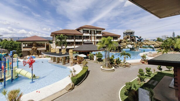 A resort with a large pool area, a water slide, and a building with multiple balconies. - Cebu Westown Lagoon-Partywing (Mandaue)