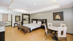 A modern hotel room with a large bed, a desk, a chair, a dining table, and a wall-mounted artwork. - Cebu Westown Lagoon-Partywing (Mandaue)