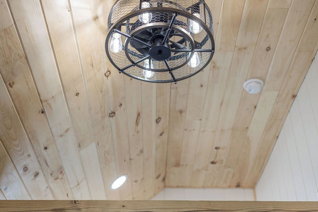 A ceiling with a circular metal chandelier and wooden paneling.