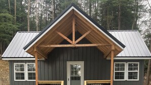 A cabin with a front porch, a door, and two windows. - Hill Side Suite (Little Valley)