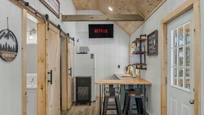 A compact kitchen with a wooden ceiling, a Netflix sign, and a rustic decor. - Hill Side Suite (Little Valley)