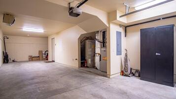 A spacious garage with concrete floors, a large black door, and a ceiling-mounted projector.
