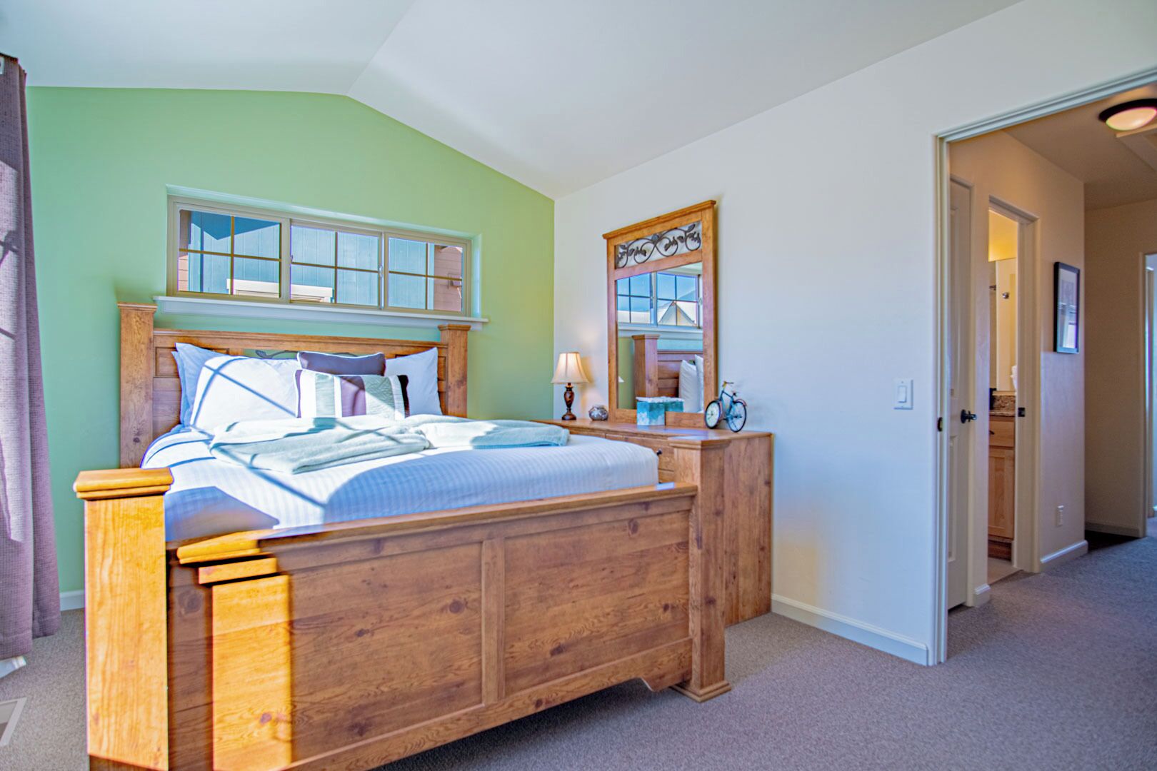 Un dormitorio con una cama de madera, una ventana, un espejo y una puerta que da a otra habitación.