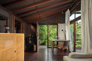 A room with a wooden ceiling, a table with chairs, a sofa, and a view of lush greenery through large windows. - Sumeru Botanical Estate (Ubud)