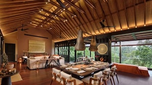 A spacious dining area with a long table set for a meal, surrounded by wooden chairs.