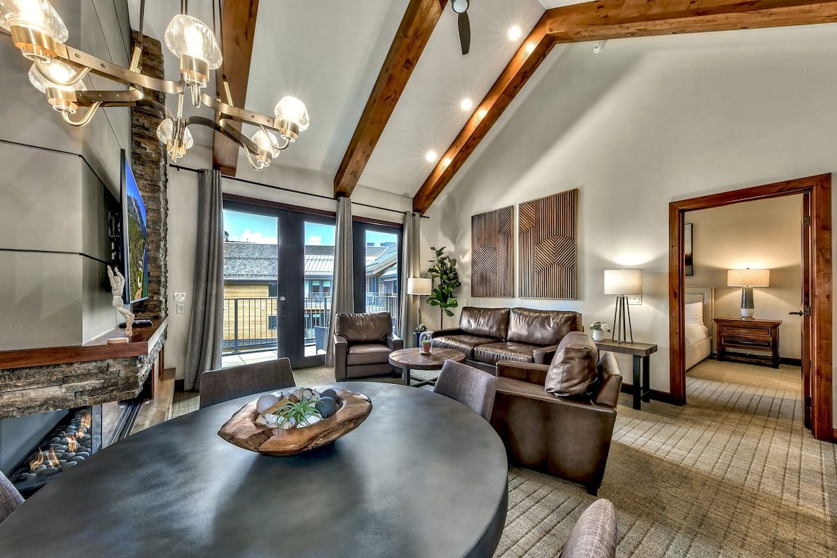 A spacious living area with a fireplace, modern furniture, and a large window offering a view of the outdoors.