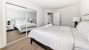 Et moderne hotelværelse med en stor seng, et sengebord, et spejl og et garderobeskab.