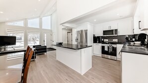 A modern kitchen with white cabinetry, a large island, and stainless steel appliances.