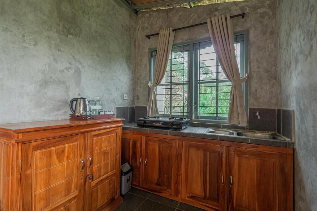 A kitchen with wooden cabinets, a window with curtains, and a sink.