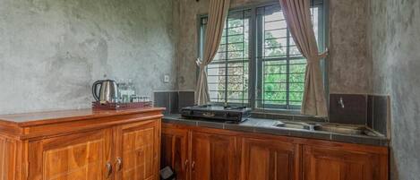 A kitchen with wooden cabinets, a window with curtains, and a sink.