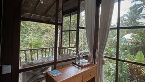 A wooden desk with a view of lush greenery outside. - Kebun Kita Ecolodge (Pupuan)