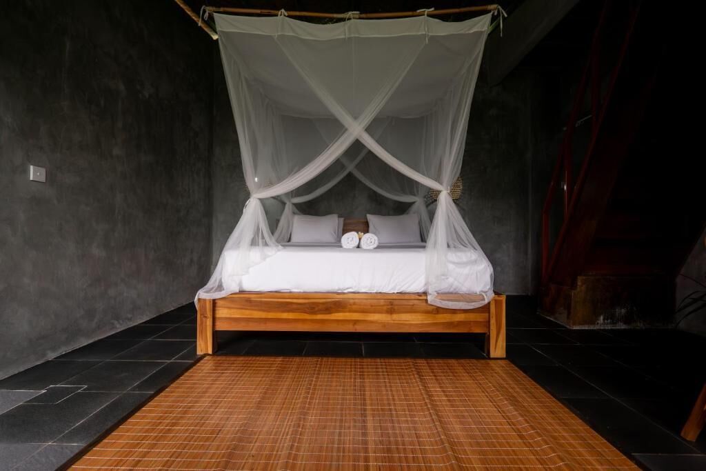 A bed with a canopy, a wooden headboard, and a bamboo mat.