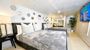A modern bedroom with two beds, a mirror, wall decor, and a TV. - Saldana Townhouse (San Juan)