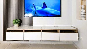 A modern living room with a flat-screen TV mounted on a white entertainment unit. - Saldana Townhouse (San Juan)